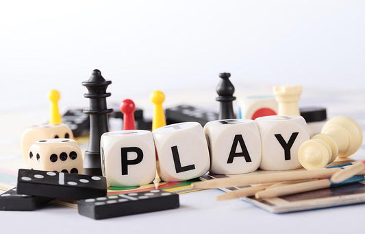 A variety of game pieces laid out with dice spelling play in the middle